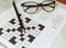 Pencil and glasses on the paper with solved crossword puzzle