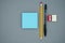 Pencil, pen, scraper, eraser and blue blank sticky notes, on a gray background, top view. School office supplies