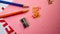 Pencils of orange and blue, a pencil sharpener lie on pink paper, and letters on white