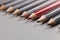 Pencils tips put on grey surface in strict order, red one among black pens