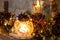 Penguin next to a candle on a mantlepiece with Christmas pinecone garland and golden leaf fairy lights