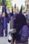 Penitent dressed in purple tunic of velvet resting on wooden cross during atonement station on Holy Week, Andalusia, Spain