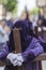 Penitent dressed in purple tunic of velvet resting on wooden cross during atonement station on Holy Week, Andalusia, Spain