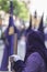 Penitent dressed in purple tunic of velvet resting on wooden cross during atonement station on Holy Week, Andalusia, Spain