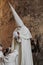 A penitent walks in front of a graffiti in the procession of Holy Week