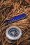 Penknife and compass on forest floor of pine needles