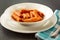 Penne Amatriciana fresh pasta with parmesan cheese on dark background
