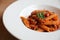 Penne arrabiata pasta tomato sauce with spices italian food on wood background