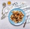 Penne with meatballs Sicilian by on a blue plate with a fork and spices on a checkered napkin rustic wooden background close u