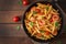 Penne pasta with tomato sauce with sausage, tomatoes, green basil decorated in a frying pan.
