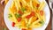 Penne pasta with yellow and red tomatoes decorated with basil on wooden background, low-calorie diet food, long width