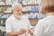Pensioner buying pill bottle in drugstore.