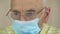 Pensioner in disposable mask and glasses in isolation