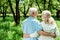 Pensioner hugging happy senior wife while standing in green park