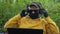 Pensioner in mask puts on headphones holding laptop closeup