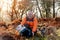 Pensioner in orange coat with English bulldogs in forest, going for a walk in Peak District on sunny worm  day. Dog