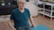 Pensioner using resistance band to stretch muscles on yoga mat