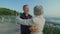 Pensioners dancing on terrace of building, hugging, whirling together