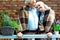 Pensioners smiling while standing in plaid blankets near flower pots