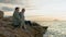 pensioners on vacation, cheerful elderly man and woman enjoying their vacation sitting on seashore on a warm evening