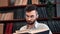 Pensive academic student teacher hipster man learning vintage paper book library cupboard closeup