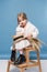 pensive adorable little girl in white dress holding wheat ears and straw boater studio shot