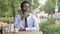 Pensive African Businessman Thinking while Sitting in Outdoor Cafe