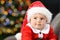 Pensive baby wearing santa costume in christmas