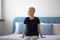 Pensive bald woman sitting on bed, thinking of cancer fight.