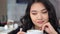 Pensive beautiful Asian young woman thinking and enjoying drinking coffee close-up portrait