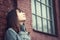 Pensive beautiful young girl standing near a brick wall