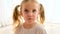 Pensive blonde little girl with pigtails looks in camera
