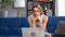 Pensive blonde woman thinking worried about problem sitting on couch in front of laptop pc at home