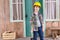 Pensive boy in helmet with hammer on porch looking away