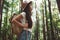 Pensive brave woman with backpack traveling alone among trees in forest on outdoors