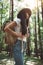 Pensive brave woman with backpack traveling alone among trees on outdoors. Young traveler girl hiking in forest