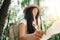 Pensive brave woman with backpack traveling alone among trees on outdoors. Young traveler girl hiking in forest and looking locati