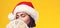 Pensive brunette woman in christmas hat holding money. Girl dreaming in Christmas. Isolated on yellow background, copy space.