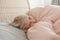 Pensive Caucasian blonde child girl lying on pillow under blanket in bed at home. Sad kid in stress or frustration. Child lying