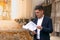 Pensive caucasian realtor in classic tie suit standing outside hold clipboard with papers and read document