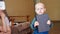 A pensive child holds a large black religious book in his hands, mom with closed eyes in the background