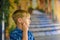 A pensive and cute boy against the background of the old city steps looks away