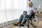 Pensive disabled senior grandma sit on wheelchair look through window