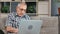 Pensive elderly business man chatting surfing internet use laptop sitting on couch at home