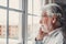 Pensive elderly mature senior man in eyeglasses looking in distance out of window, thinking of personal problems. Lost in thoughts