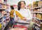 Pensive elderly woman choosing vegetable oil in supermarket
