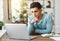 Pensive ethnic man using laptop at home