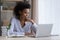 Pensive ethnic woman sit at desk work on laptop