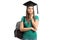 Pensive female student with a graduation hat and a backpack