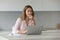 Pensive freelancer woman working on laptop at home